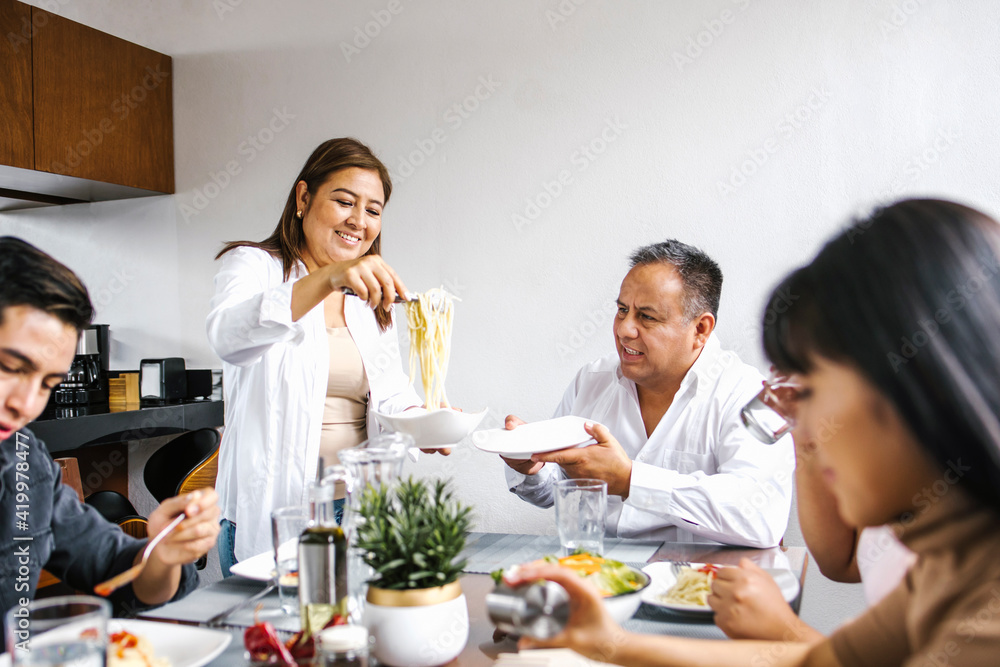 mexican family eating pasta together in home in Mexico city mexican family eating pasta together in home in Mexico city