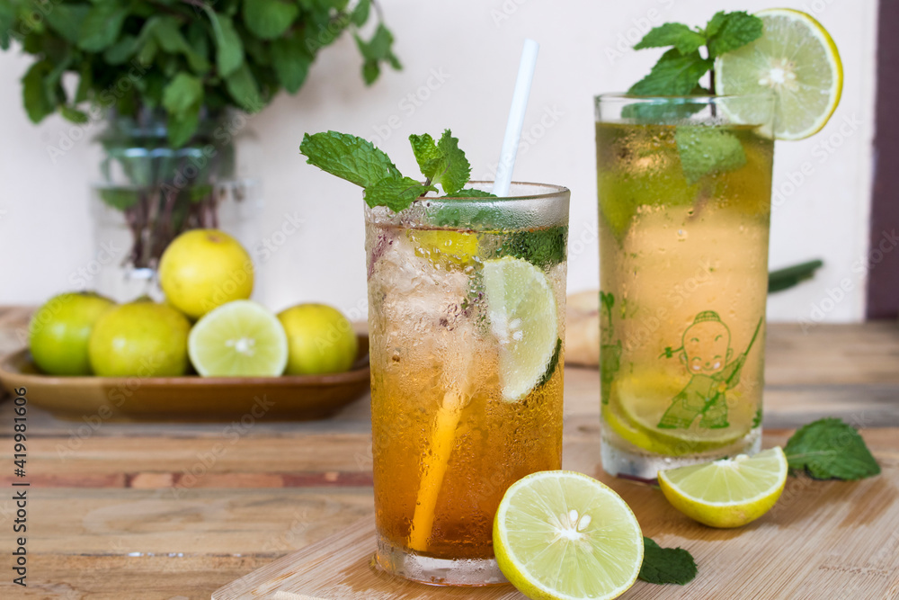 Fototapeta premium herbal healthy drinks cold lemon tea for health care with peppermint leaf and lemon slice arrangement flat lay style on background wooden