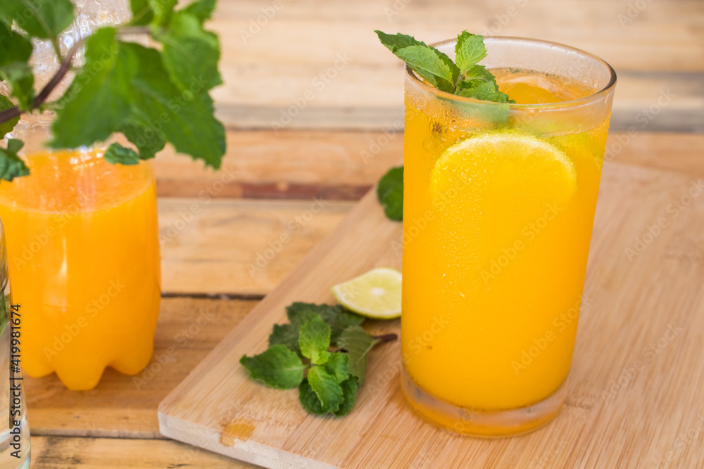 Fototapeta premium herbal healthy drinks cold orange juice for health care with peppermint leaf and lemon slice arrangement flat lay style on background wooden