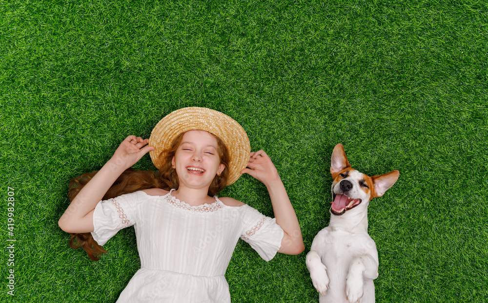 Laughing girl and cute dog enjoy summer day on the grass - obrazy, fototapety, plakaty 