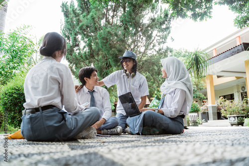 a male student wearing headphones and sunglasses meets three high school students while studying in a group with friends
