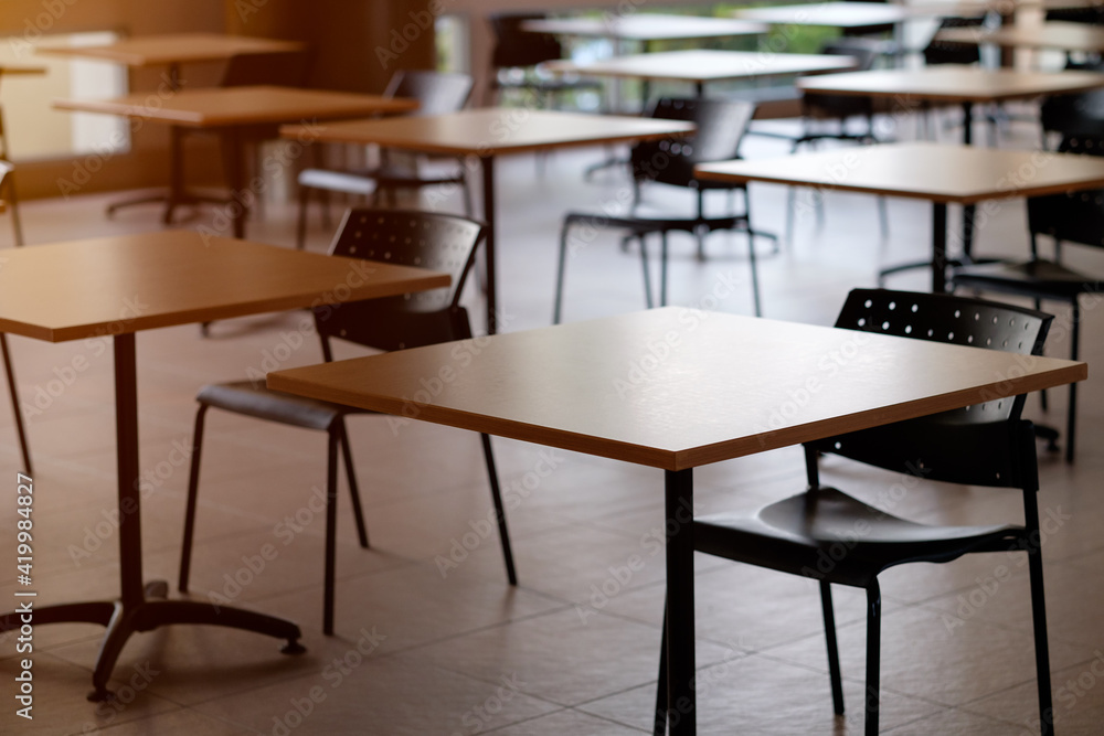 Tables and chairs that is arranged spaced or social distancing in the dining room without people. Tables and chairs that is arranged spaced or social distancing in the dining room without people.