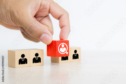 Hand choosing people icon on cube wooden toy block stacked. Concepts of human resources personnel selection and person organization job fit and employees performance.