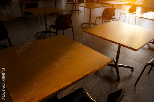 Tables and chairs that is arranged spaced or social distancing in the dining room without people.