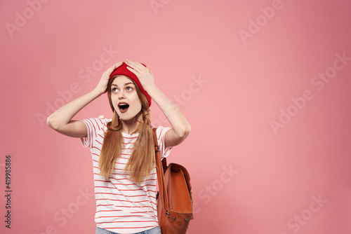 Fashionable glamorous woman in red hat backpack student hipster pink background