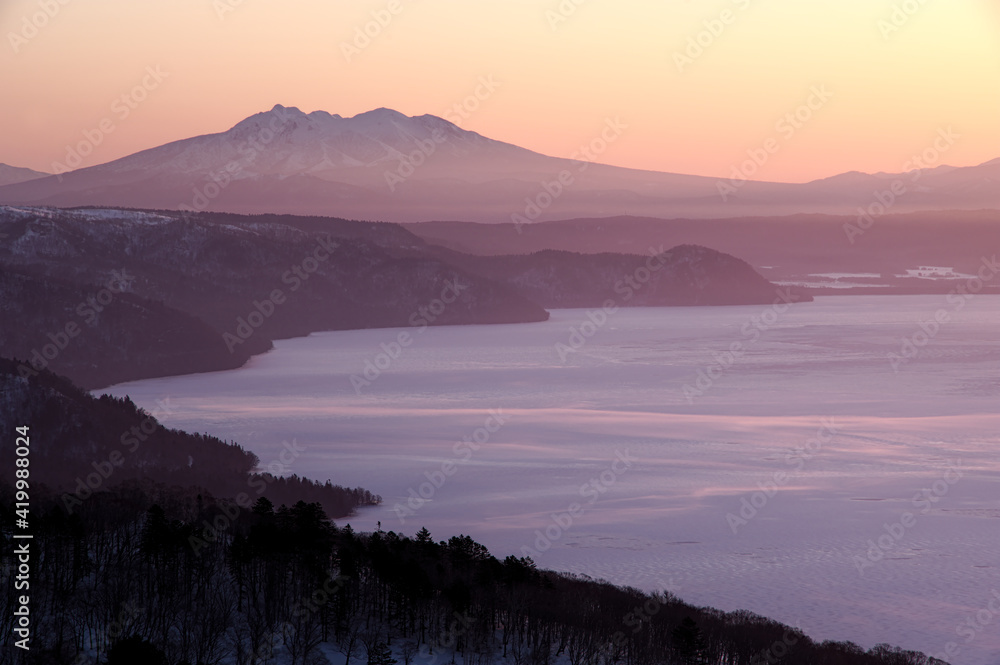 早朝の高所から見る遠くの山の稜線と眼下の湖。日本の北海道の観光地の美幌峠からの屈斜路湖と斜里岳の眺め。