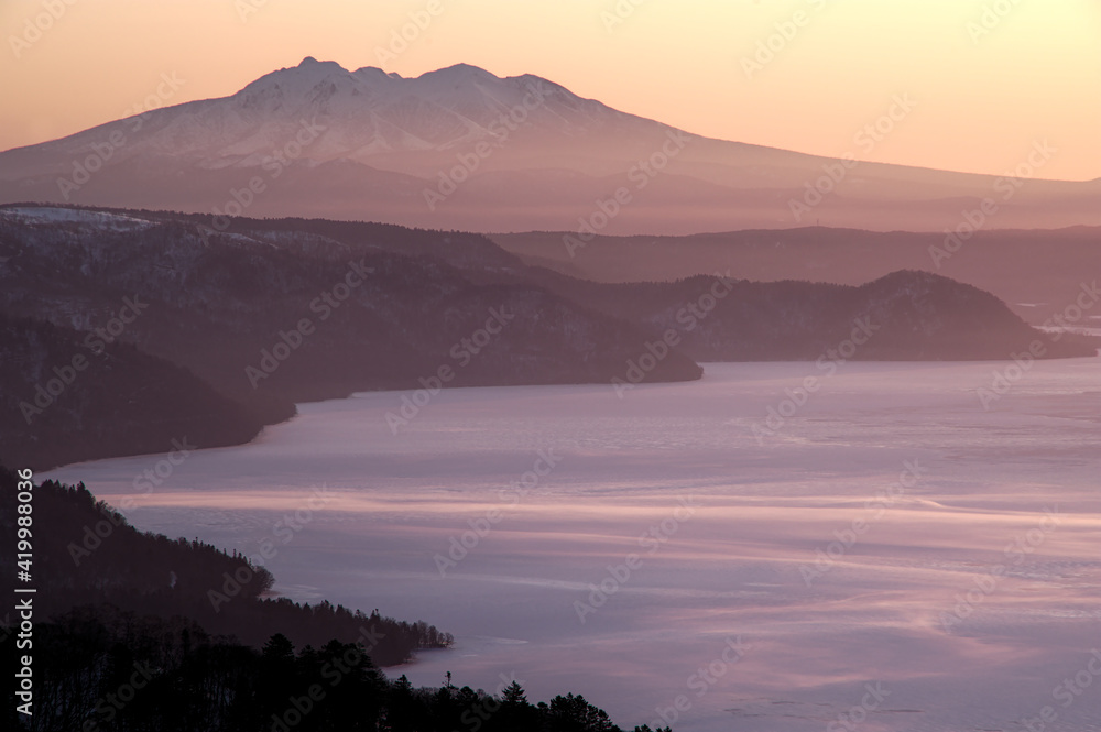 早朝の高所から見る遠くの山の稜線と眼下の湖。日本の北海道の観光地の美幌峠からの屈斜路湖と斜里岳の眺め。