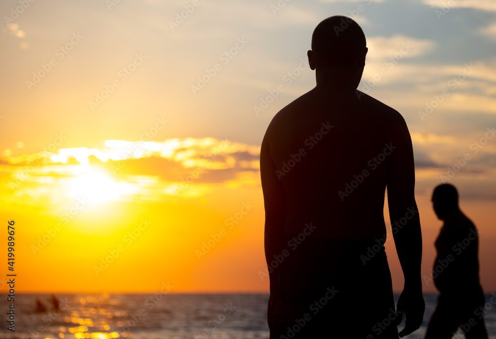 Silhouette of two men by the sea