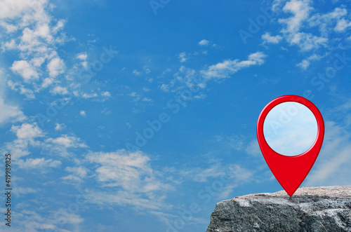 Map pin location button on rock mountain over blue sky with white clouds, Map pointer navigation concept