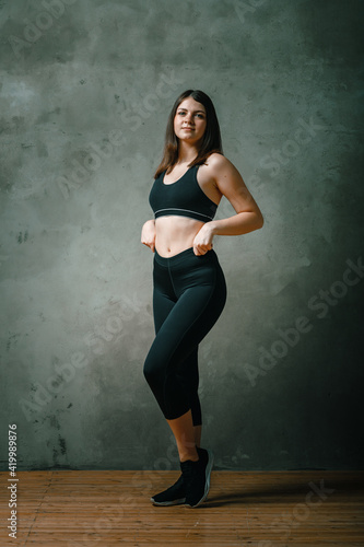 A strong and beautiful sports fitness girl in sportswears posing on a dark gray background