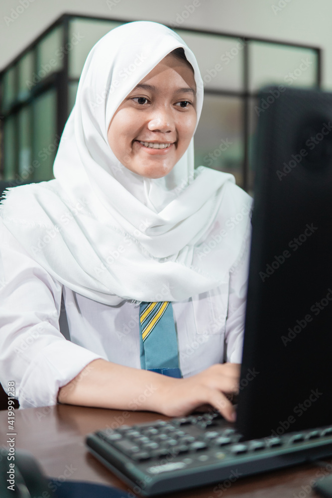 close up of a female student in a veil typing a keyboard close up of a female student in a veil typing a keyboard