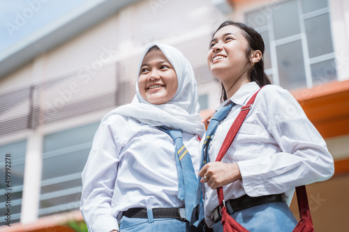 close up of two beautiful student wearing an Indonesian high school uniform and bag standing