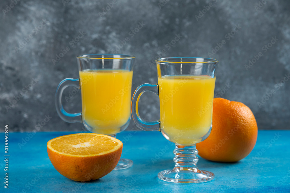 Two glass cups of juice with slice of orange