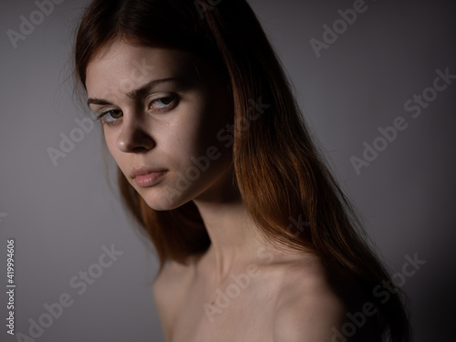 Red-haired woman naked shoulders side view dark background portrait close-up
