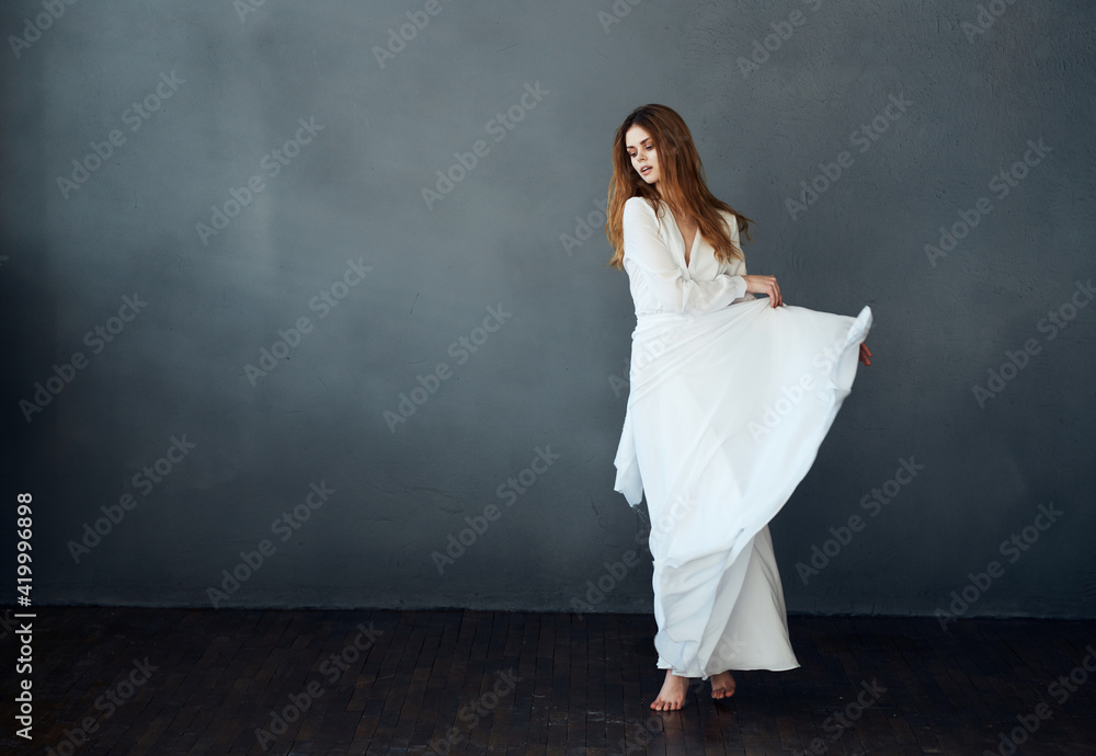 Charming lady in a white dress on a gray background dance gesticulating with her hands model Charming lady in a white dress on a gray background dance gesticulating with her hands model