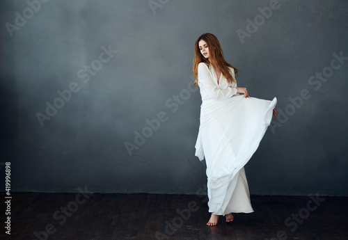 Charming lady in a white dress on a gray background dance gesticulating with her hands model