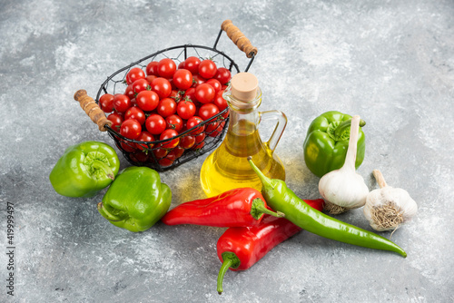 Fototapeta Naklejka Na Ścianę i Meble -  Cherry tomatoes in basket with chili peppers, garlic and olive oil