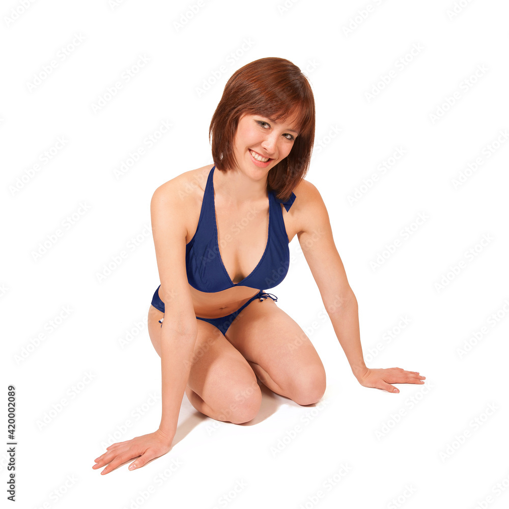 Attractive young women kneeling, she is wearing a blue bikini, isolated on white studio background Attractive young women kneeling, she is wearing a blue bikini, isolated on white studio background