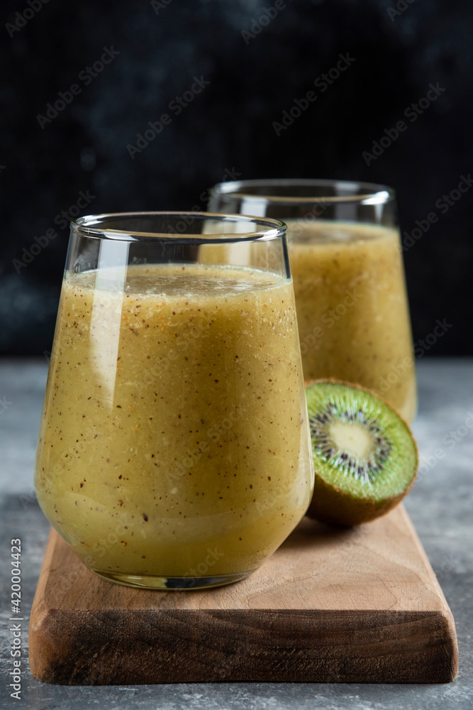 Two glass cups of kiwi juice on a wooden board Two glass cups of kiwi juice on a wooden board