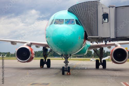 Passenger plane at the airport. Boarding passengers through the boarding bridge. Loading and unloading of baggage. Passenger aircraft on the runway. Plane landing. Cocpit. Copy space. Travel.