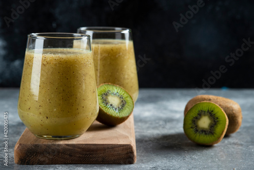 Two glass cups of tasty kiwi juice on a wooden board