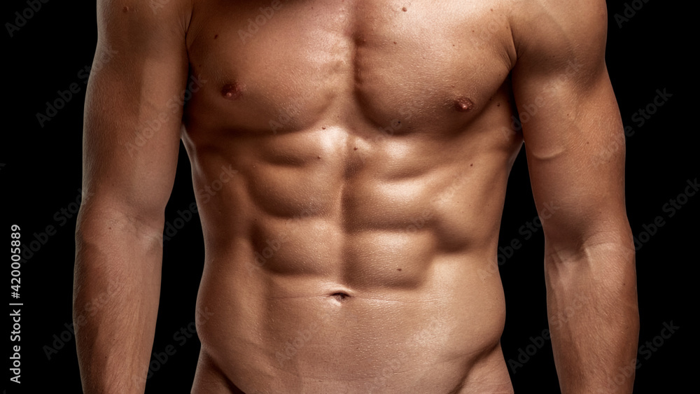 Closeup image of a strong athletic man showing muscular body and sixpack abs isolated black background.