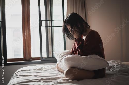 woman suffering from depression sitting on the bed in the bedroom
