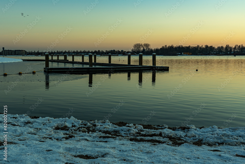 The sun has just set over this boat dock in a wintry lake Zoetermeerse Plas