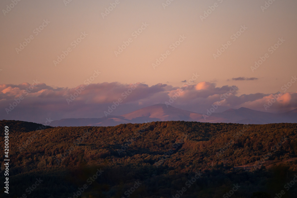fall landscape overlooking the horizon where the ridges of the high mountains can be seen. high hills full of dense forests at sunset