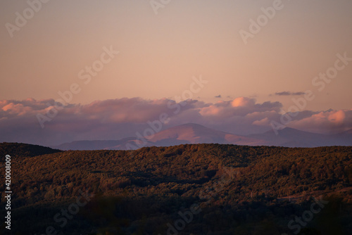 fall landscape overlooking the horizon where the ridges of the high mountains can be seen. high hills full of dense forests at sunset