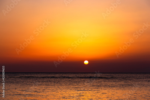 Bright sunset with a big yellow sun under the sea surface.