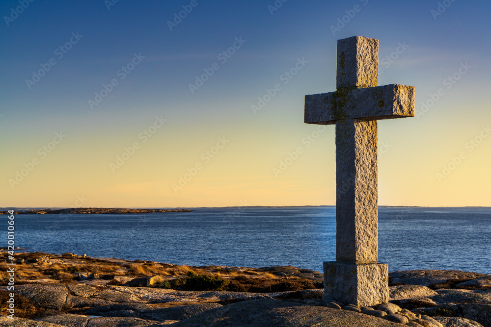 Catholic cross towering over the fjord, golden hour
