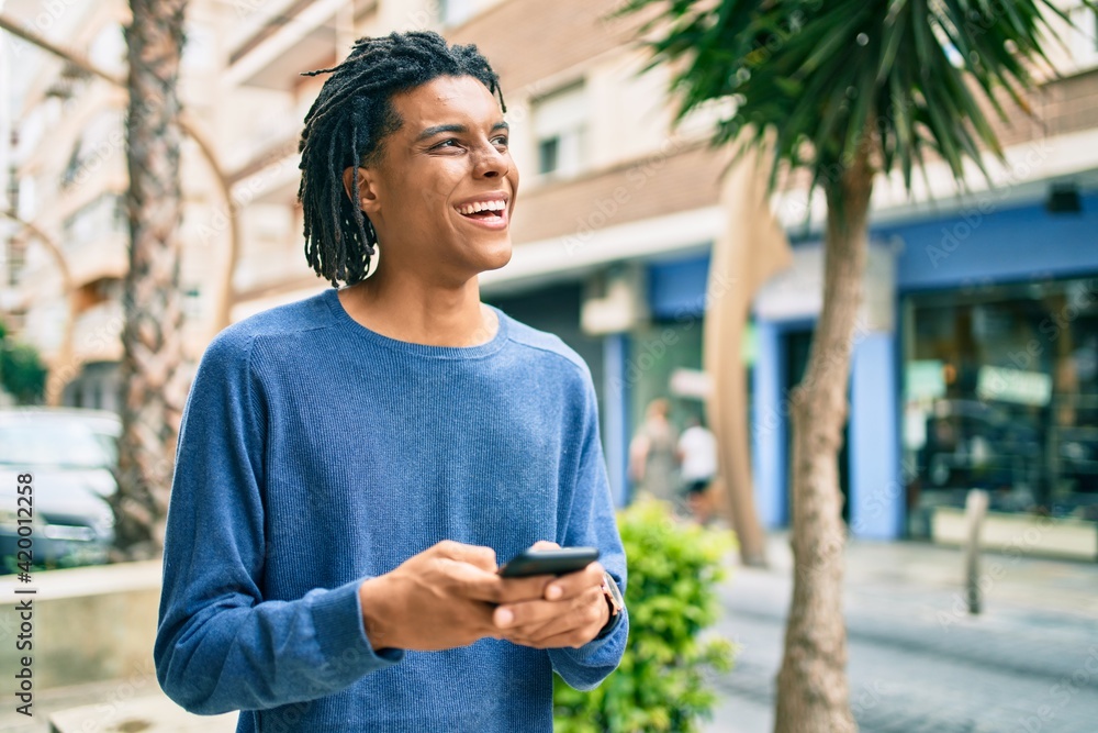 Young african american man smiling happy using smartphone at street of city. Young african american man smiling happy using smartphone at street of city.