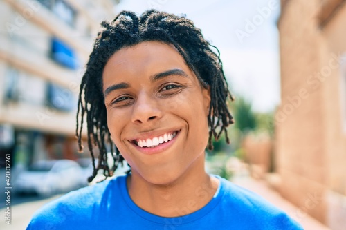 Young african american man smiling happy looking to the camera at street of city.