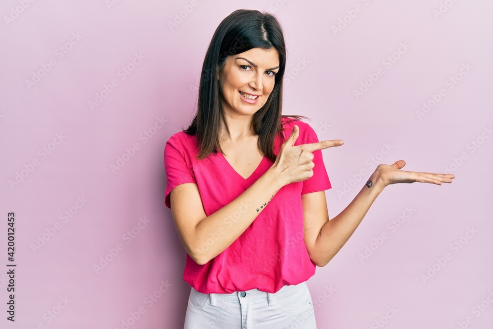 Young hispanic woman wearing casual clothes amazed and smiling to the camera while presenting with hand and pointing with finger. Young hispanic woman wearing casual clothes amazed and smiling to the camera while presenting with hand and pointing with finger.