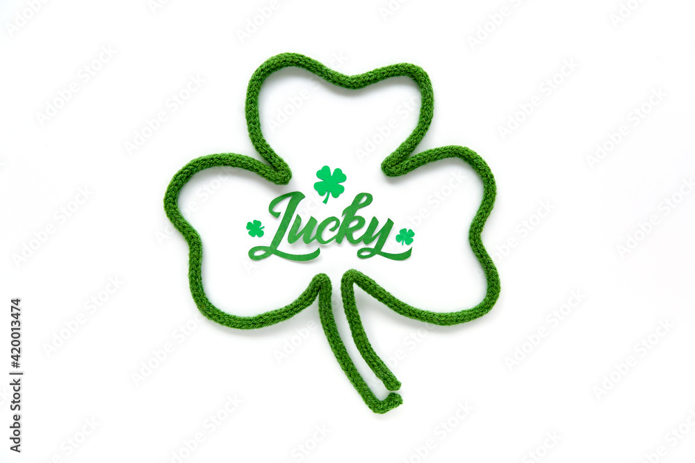 Lucky word - St. Patrick's day lettering. Brush calligraphy design with clover shamrock leaf. Greeting cards. Soft focus. Top view. Lucky word - St. Patrick's day lettering. Brush calligraphy design with clover shamrock leaf. Greeting cards. Soft focus. Top view.
