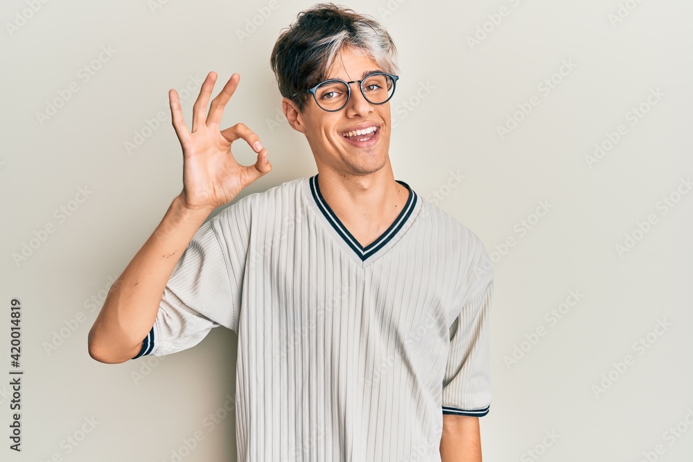 Young hispanic man wearing casual clothes and glasses smiling positive doing ok sign with hand and fingers. successful expression. Young hispanic man wearing casual clothes and glasses smiling positive doing ok sign with hand and fingers. successful expression.