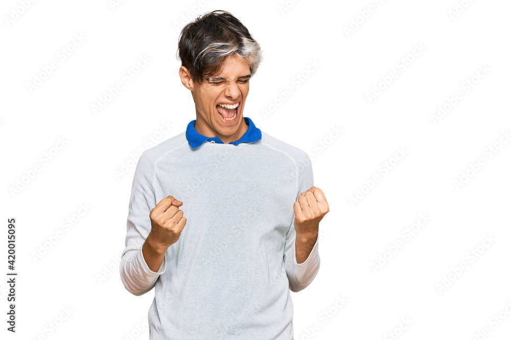 Young hispanic man wearing casual clothes very happy and excited doing winner gesture with arms raised, smiling and screaming for success. celebration concept. Young hispanic man wearing casual clothes very happy and excited doing winner gesture with arms raised, smiling and screaming for success. celebration concept.