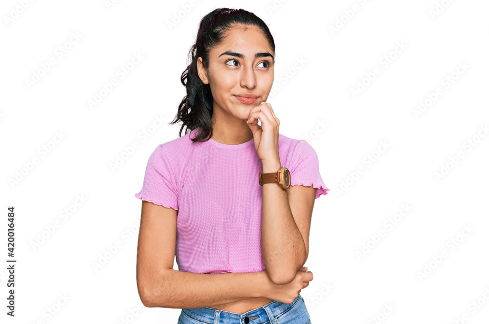 Hispanic teenager girl with dental braces wearing casual clothes with hand on chin thinking about question, pensive expression. smiling and thoughtful face. doubt concept. Hispanic teenager girl with dental braces wearing casual clothes with hand on chin thinking about question, pensive expression. smiling and thoughtful face. doubt concept.