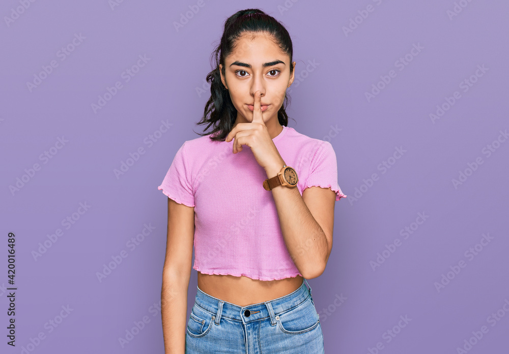 Hispanic teenager girl with dental braces wearing casual clothes asking to be quiet with finger on lips. silence and secret concept. Hispanic teenager girl with dental braces wearing casual clothes asking to be quiet with finger on lips. silence and secret concept.
