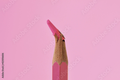 Close-up of broken tip of pink colored pencil on pink background - Concept of violence against women photo