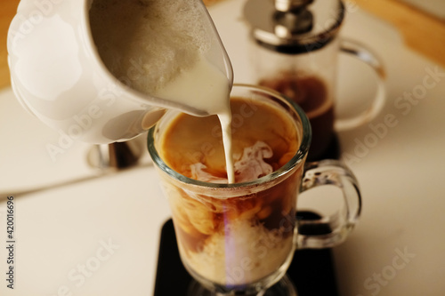 Milk coffee preparation process. Lightly whipped cream is poured into the coffee. Latte in irish glass