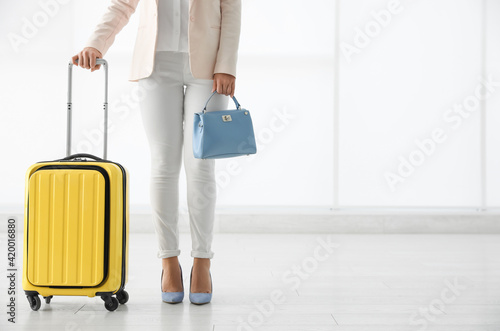 Businesswoman with yellow travel suitcase in airport. Space for text