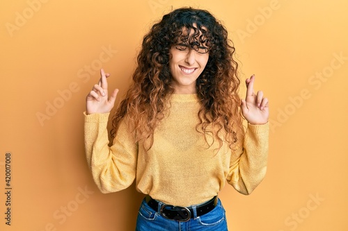 Young hispanic girl wearing casual clothes gesturing finger crossed smiling with hope and eyes closed. luck and superstitious concept. © Krakenimages.com