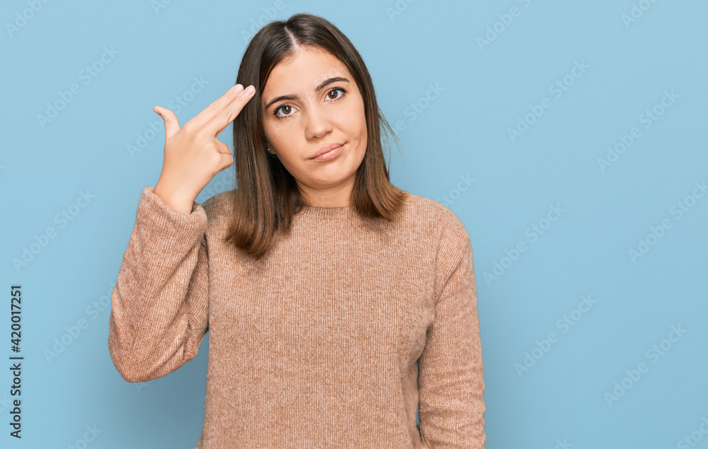 Young beautiful woman wearing casual clothes shooting and killing oneself pointing hand and fingers to head like gun, suicide gesture. Young beautiful woman wearing casual clothes shooting and killing oneself pointing hand and fingers to head like gun, suicide gesture.