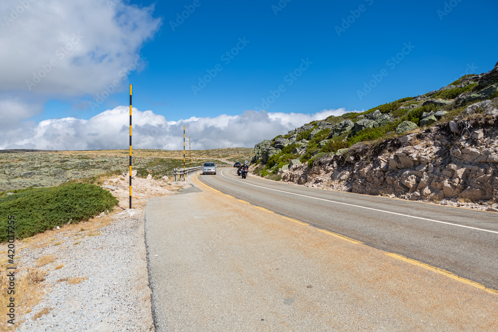 View of road uphill in the Serra da Estrela natural park, with bikers on ride and cars...