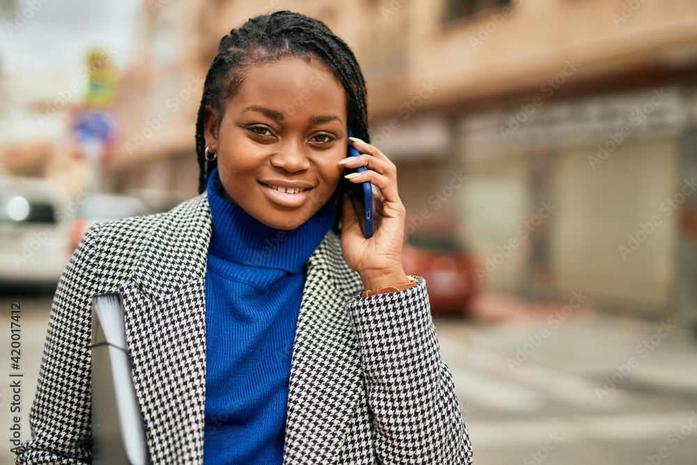 Young african american businesswoman smiling happy talking on the smartphone at the city. Young african american businesswoman smiling happy talking on the smartphone at the city.