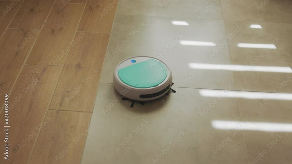 Robotic vacuum cleaner disinfecting floor surface driving around living room. Apartment cleaning. Modern automated clean robot machine. Robotic vacuum cleaner disinfecting floor surface driving around living room. Apartment cleaning. Modern automated clean robot machine.