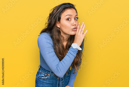 Young hispanic girl wearing casual clothes hand on mouth telling secret rumor  whispering malicious talk conversation