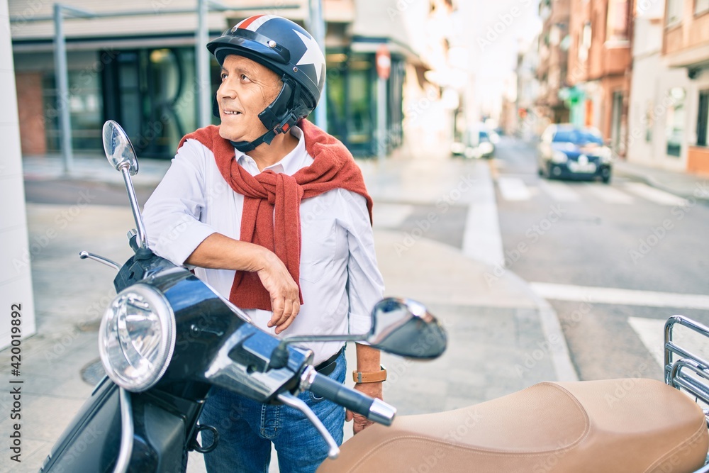 Senior motorcyclist man smiling happy wearing moto helmet at the city.